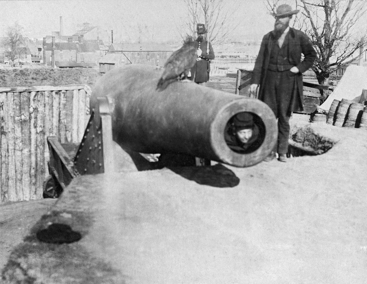 Russian sailor poses with large owl in 15-inch Rodman smoothbore, Battery Rodgers, near Alexandria Va.