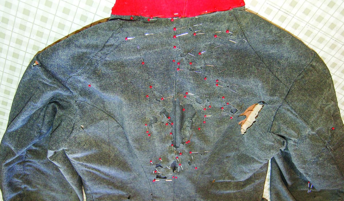 Patches pinned into the holes on the top back of the coat.