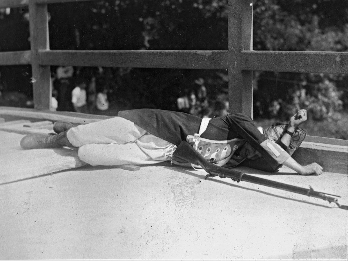 A British casualty, actually a Mass. National Guardsman, lies on Concord Bridge in 1930, his Model 1873 Springfield by his (Joseph Bilby Collection)