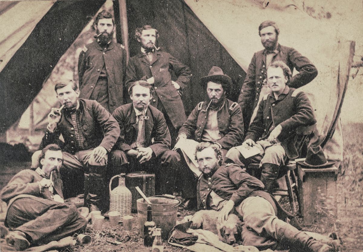 Staff of Gen. Fitz-John Porter posing in front of a tent with drinks, pipes, and a dog during the Peninsular Campaign, Va.; Lieutenant William G. Jones and Lieutenant George A. Custer in front. May 20, 1862. Library of Congress.