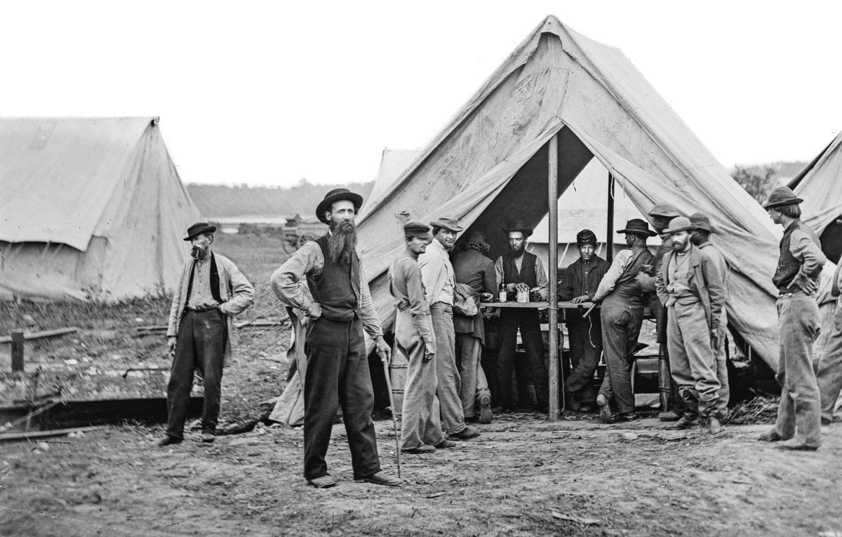 Customers gather around the sutler’s tent to purchase items such as wine, beer, and other alcohol. These men are from the Union 2nd Division, IX Corps, at Petersburg, Va. Library of Congress.