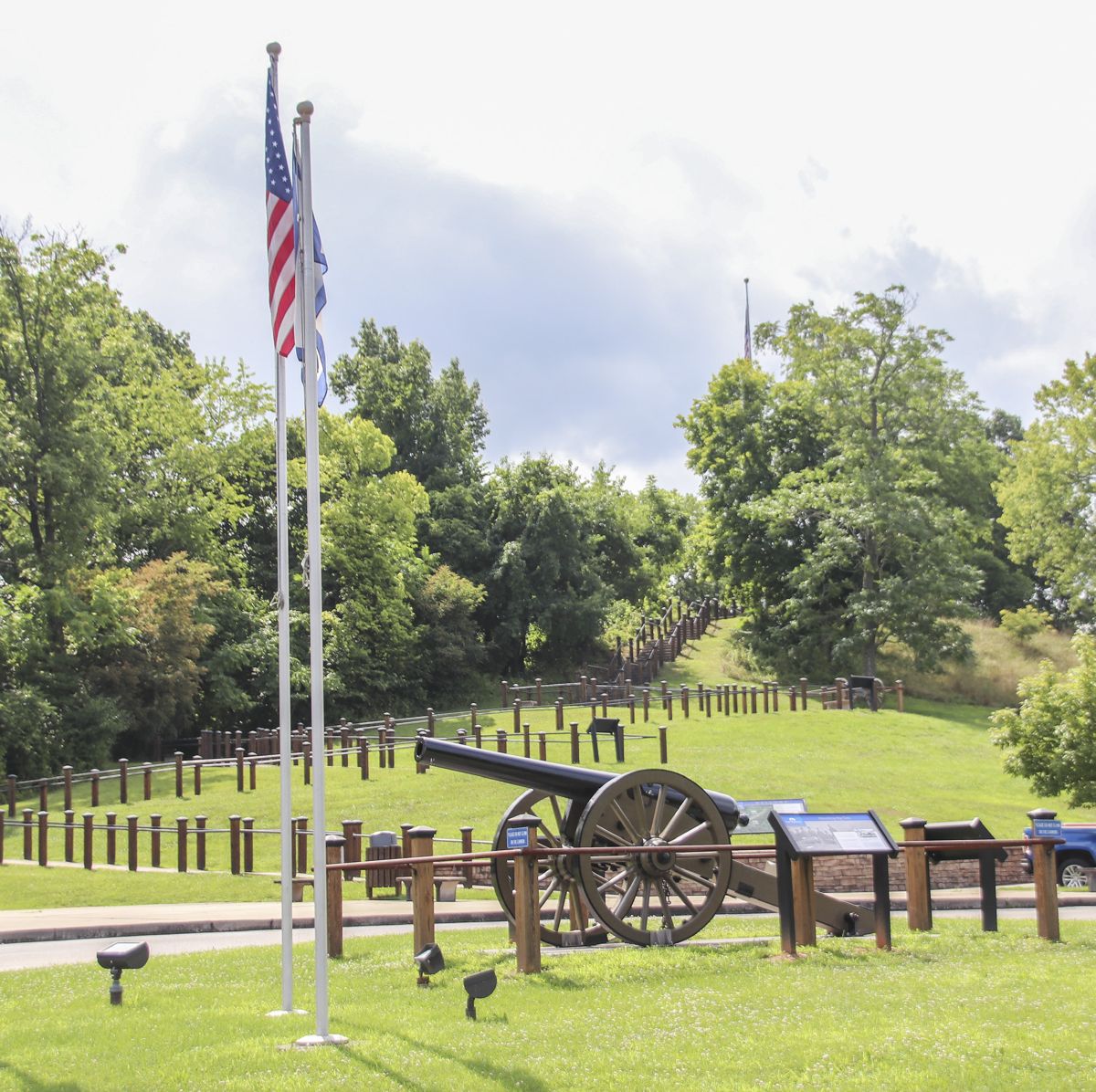 A view of the siege gun in its own plot of land with a hiking train beyond.