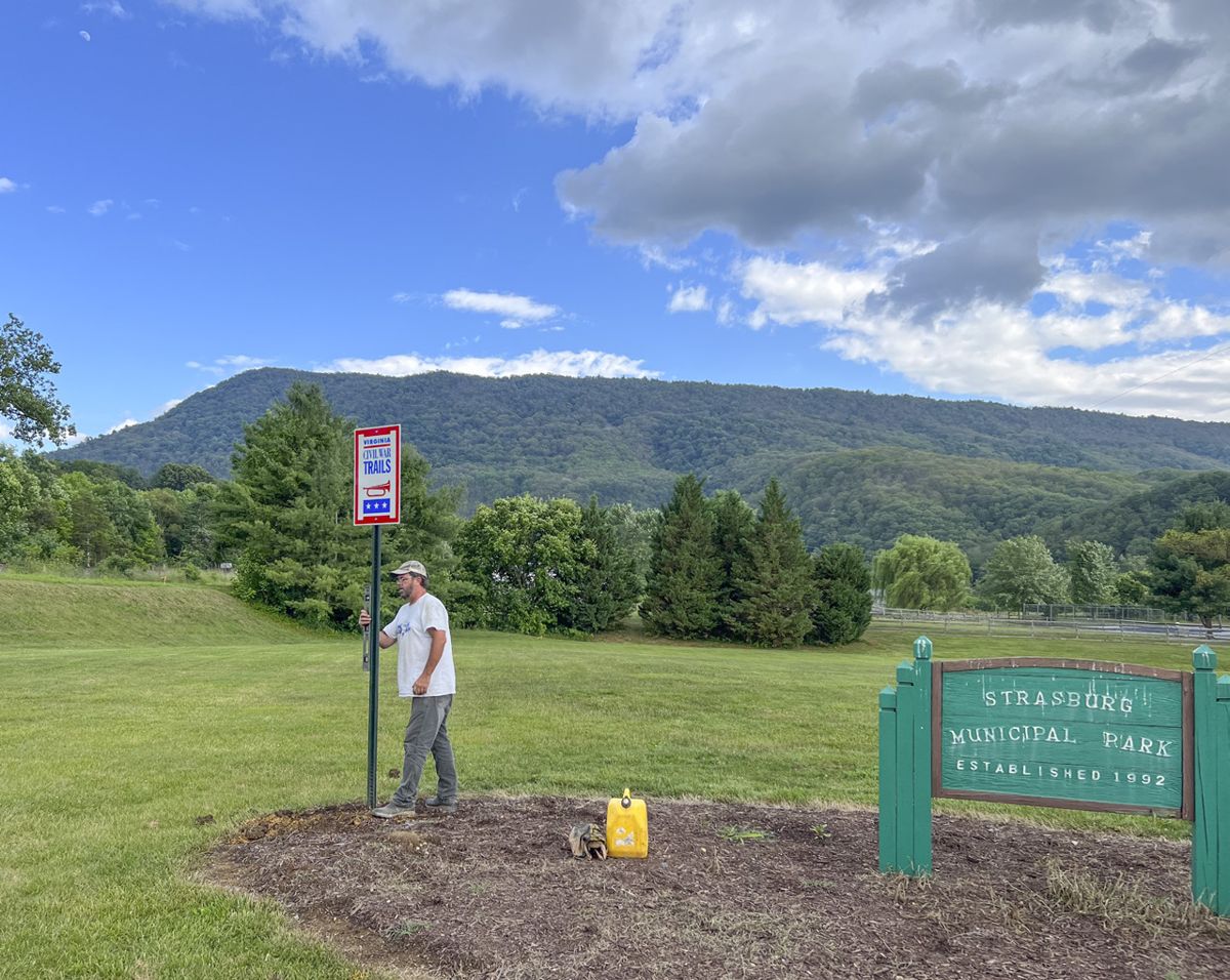 Jason Shaffer, Operations Manager for Civil War Trails installs the confirmatory directional sign for the new Signal Knob stop in Strasburg Municipal Park.