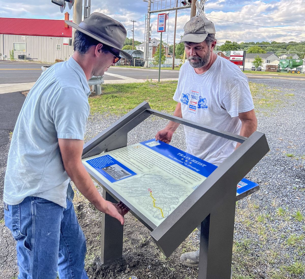 Chris Brown (left), Assistant Director of Civil War Trails and Jason Shaffer lift the new sign at the Museum into place.